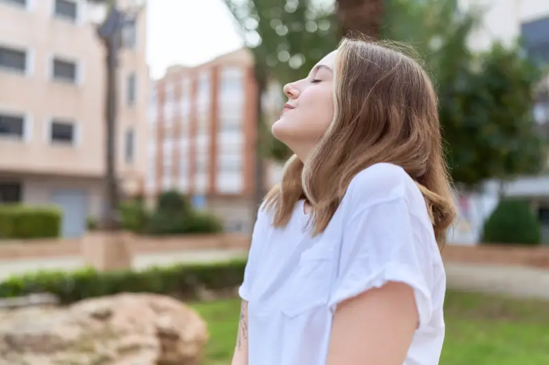 woman breathing with closed eyes at park